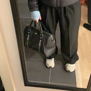 Zadig & Voltaire väska - Snygg svart skinnväska med coola dragkedjedetaljer och dubbla handtag. Perfekt för att ge din outfit en edgy touch. Väskan har även en justerbar axelrem för extra bekvämlighet. Väskan är i nyskick och bara använd ett fåtal gånger, nypris 6100kr. Den största modellen av sunny bag.