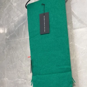 Grön halsduk från Stuhf - Snygg grön halsduk från Stuhf med fransar i ändarna. Perfekt för att liva upp din outfit med en färgklick. Nypris 499kr