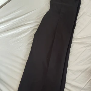 Svarta byxor från Madlady - Snygga svarta byxor från Madlady i storlek M. Perfekta för en stilren look med en rak passform. Byxorna är tillverkade i ett bekvämt material som passar till många olika tillfällen.