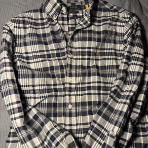 Flanell skjorta från Polo Ralph Lauren - Snygg rutig skjorta från Polo Ralph Lauren i blått och vitt. Skjortan är använd få gånger. Perfekt för en stilren look. Dels för avslappnade häng, men också för mer finare tillställningar. 