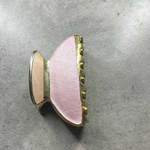 Hårklämma i guld och rosa - Elegant hårklämma i guld med rosa detaljer. Perfekt för att hålla håret på plats med stil. Den har en glansig finish och en mjuk rosa yta som ger en lyxig känsla.