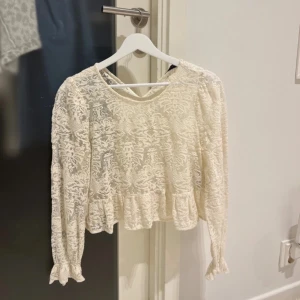 Vit spetsblus  - Säljer en jättefin vit spetsblus från Zara Basic Collection. Blusen har långa ärmar och en fin volangdetalj vid nederkanten. Perfekt till fest eller middagar!!! Där bak där man spänner fast knappen har gått sönder men inget som påverkar hur den sitter på🤗Storlek M men passar S. Den är cremevit/vit