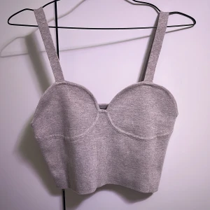 Grå ribbad linnetopp från H&M - Snygg grå ribbad linnetopp från H&M med breda axelband och en stilren design. Perfekt för en avslappnad look eller att styla upp med accessoarer. Passar bra till både jeans och kjol.