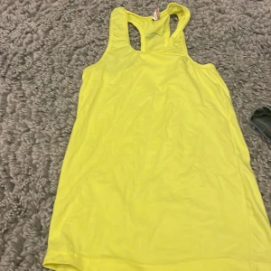 Gul linnetopp från Al Karam - Säljer en solgul linnetopp från Al Karam. Perfekt för varma dagar med sin ärmlösa design och mjuka bomullsmaterial. Toppen har en enkel och stilren look.