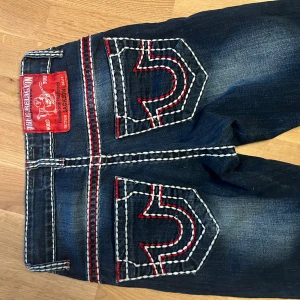 Mörkblå jeans med kontrastsömmar - Snygga mörkblå jeans med vita och röda kontrastsömmar. Klassisk femficksdesign och lågmidjad passform. Perfekta för en avslappnad stil med en touch av detaljer. XS-S