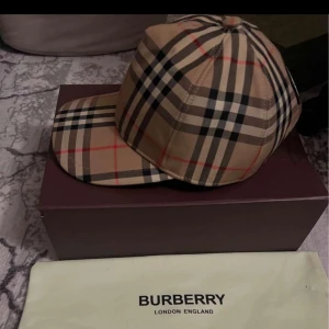  Burberry keps - Hej säljer en burberry keps som är i bra skick har använt kepsen max 1 månad och den har inga skador och fläckar osv. Kepsen kommer med dust bag och box. Hör av er för mera bilder och info!