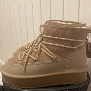 Beige moon boots med snörning - Snygga beige moon boots med snörning och mjukt foder. Perfekta för kalla dagar med sin varma och bekväma design. De har en robust sula och stilren look.