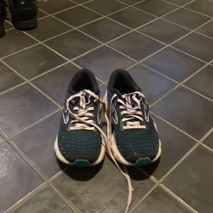 Brooks Glycerin löparskor - Säljer ett par Brooks Glycerin löparskor i mörkblått med vita och ljusrosa detaljer. Skorna har snörning och en bekväm sula för optimal dämpning under löpning.