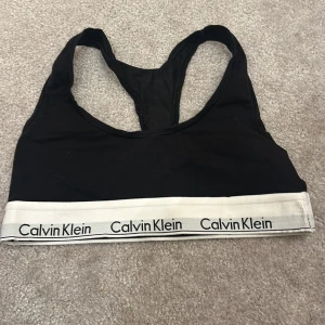 Svart linnetopp från Calvin Klein - Snygg svart linnetopp från Calvin Klein med vit resårkant och logotyp. Perfekt för en avslappnad stil.