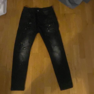 Svarta jeans med slitningar - Snygga svarta jeans med slitningar och en cool, sliten look. Perfekta för en avslappnad stil. De har en klassisk femficksdesign och en knappgylf.