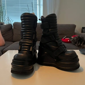 Svarta boots med platåsula - Säljer ett par svarta boots med hög platåsula och justerbara remmar. Skorna var köpta på 90-talrt och är knappast använda, nyligen proffesionellt putsade och lackade. Gjorda i fejk läder.