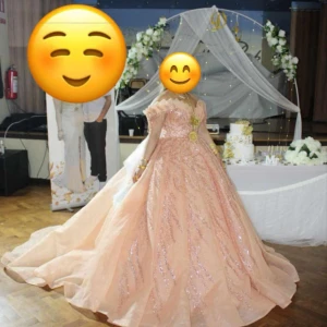 Champagnefärgad balklänning med paljetter - Elegant champagnefärgad balklänning med glittriga paljettdetaljer. Klänningen har en lång, svepande kjol och en offshoulder-design som ger en romantisk känsla. Perfekt för speciella tillfällen.