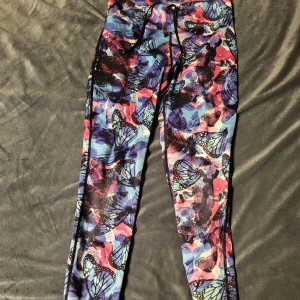 Färgglada leggings från Pro Touch - Säljer ett par färgglada leggings från Pro Touch med fjärilsmönster i blått, rosa och lila. Perfekta för träning eller en färgglad vardag. De har en tight passform och är tillverkade i ett stretchigt material.