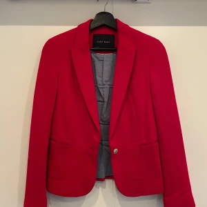 Röd kavaj från Zara Basic - Snygg röd kavaj från Zara Basic med en knapp framtill och klassisk krage. Perfekt för att ge en färgklick till din outfit. Kavajen har långa ärmar och en stilren design. 