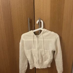 Vit stickad hoodie - Mysig vit stickad hoodie med dragkedja och huva. Perfekt för kyliga dagar.