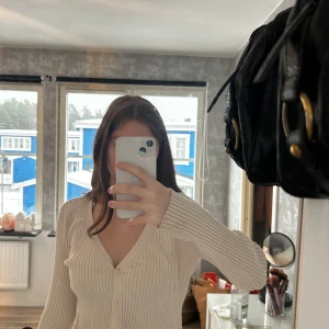 Beige ribbad kofta från H&M - ⚠️ ni betalar för frakt⚠️Säljer en stilren beige ribbad kofta från H&M. Koftan har en v-ringad design med knappar framtill och långa ärmar. Perfekt för lager-på-lager under kyligare dagar.