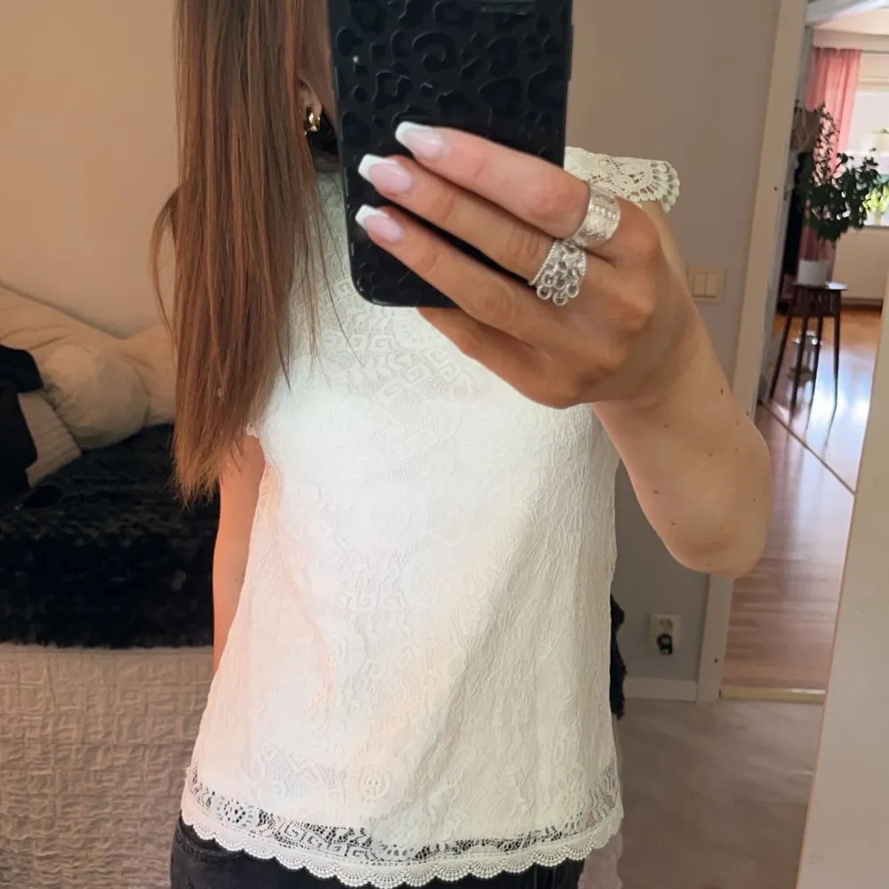 Säljer en superfin vit spetsblus med vackra detaljer. Den är ärmlös och har en söt volangkant vid ärmhålen. Perfekt för sommarens alla fester eller en dag på stan. Blusen är använd några gånger men har inga defekter!🥰❣️💕. Yläosat.