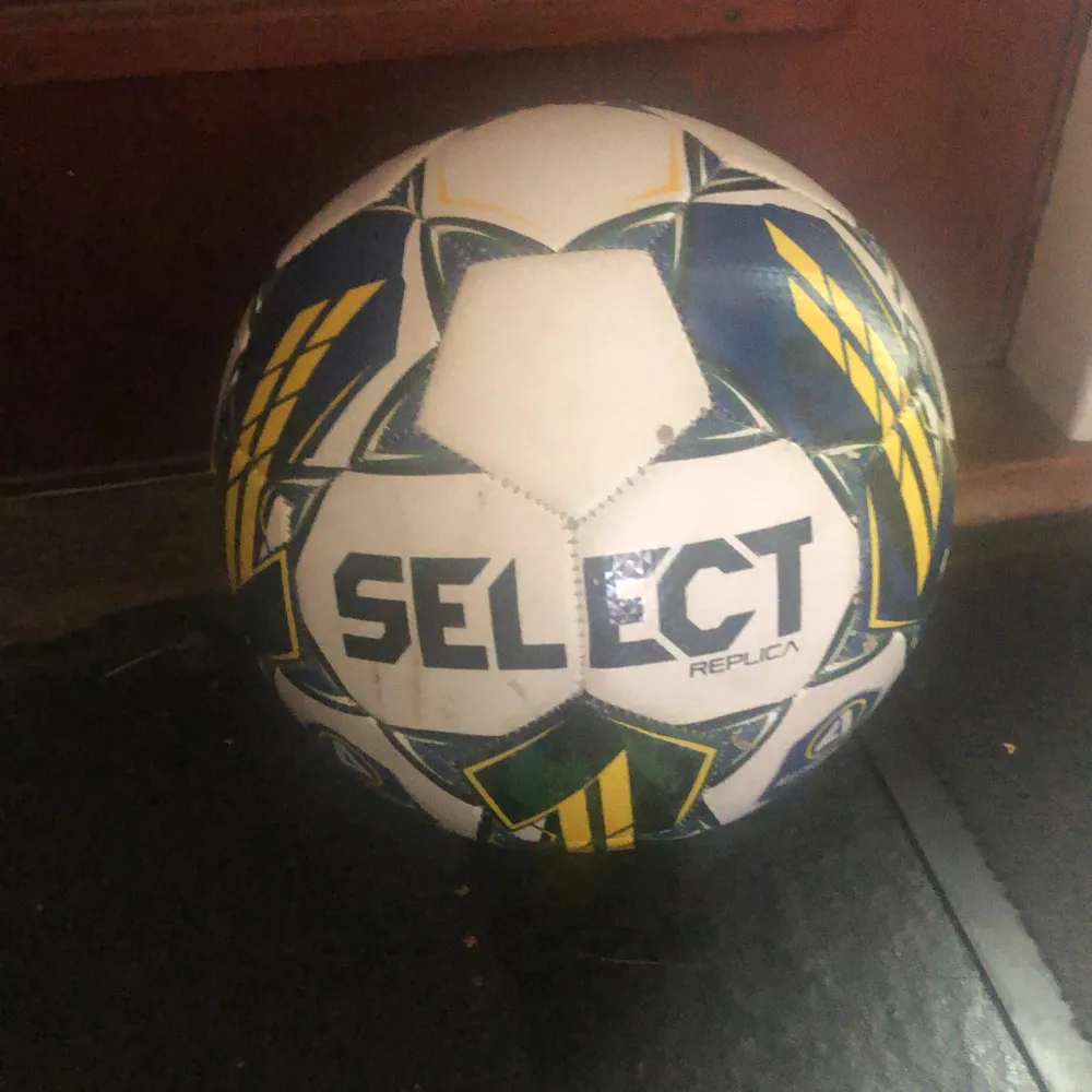 Säljer en fotboll från Select i storlek 5. Bollen har en cool design med vita, blå och gula mönster. Perfekt för träning eller match! Rekommenderat tryck är 7,3-10,2 PSI. Den är i bra skick och redo för spel.. Sportswear.