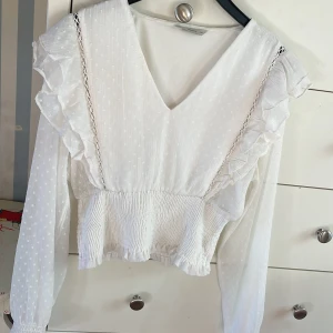 Gullig blus💘 - Säljer denna jättefina blusen då den inte kommer till användning och är för liten! Använd fåtal gånger. Den är vit och prickig, har volanger uppe vid axlarna!  Säljer den för 200kr. 