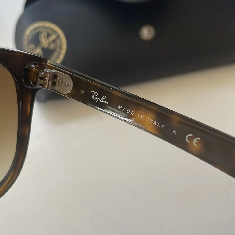 Säljer ett par snygga Ray-Ban Boyfriend solglasögon i brun färg med ett matchande svart fodral. Glasögonen är tillverkade i Italien och har en klassisk design med bruna linser. Perfekta för soliga dagar! RB 4147. Accessoarer.