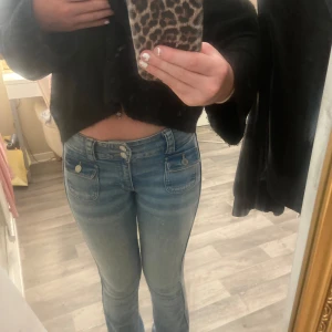 Blå bootcut jeans från H&M - Säljer ett par snygga blå bootcut jeans från H&M. De är lågmidjade och har justerbar midja för perfekt passform. Jeansen har en klassisk femficksdesign och är i ett mjukt denimtyg. Perfekta för både vardag och fest!