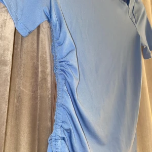 Blå träningstopp från Reebok - Säljer en snygg blå topp från bikbok, aldrig använd så i nyskick! Snygg knytdetalj samt utskärningar vid halsen