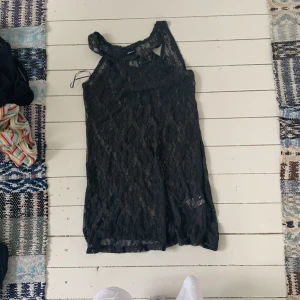 Svart spetsklänning från Gina Tricot - Säljer en elegant svart spetsklänning från Gina Tricot i storlek XL. Klänningen är ärmlös och har ett vackert blommigt mönster i spetsen. Perfekt för festliga tillfällen eller en utekväll. Den är i nyskick och redo att bäras av någon som vill känna sig extra fin!