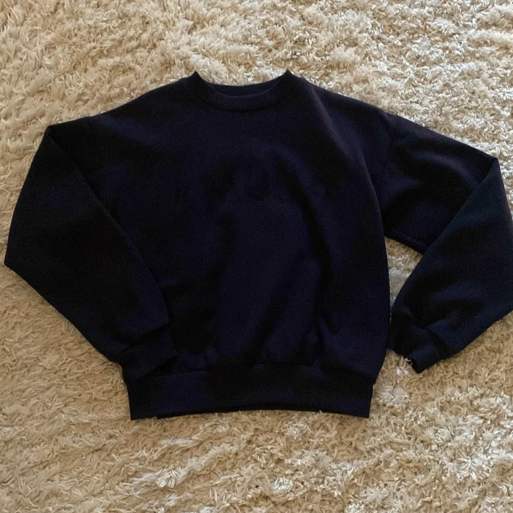 Säljer en snygg marinblå sweatshirt från Gina Tricot med texten 'AMOUR' diskret tryckt på framsidan. Tröjan är i storlek 134/140 och har långa ärmar. Perfekt för en casual look eller mysiga dagar hemma. 🖤. Tröjor & Koftor.