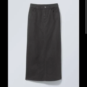 Svart långkjol i jeansmaterial - Säljer en stilren svart långkjol i jeansmaterial. Kjolen har en klassisk design med knapp och dragkedja framtill. Perfekt för både vardag och festliga tillfällen. Passar bra till höst- och vintergarderoben!