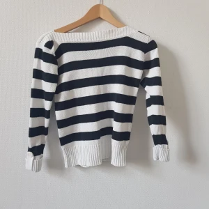 Svartvit, randig och ribbad tröja - Svartvit randig tröja, stickad och ribbad, bred neckline. Knappar på ärmarna.