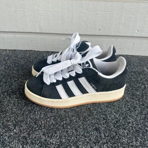 Svarta campus 00s  - Svarta adidas campus 00s. Bra skick och har tvättat snörena en gång. Jättesköna och med fina snören. Köpte dessa på Junkyard och de är i storleken 37 1/3. Liten defekt på insidan men märks bara om man känner med handen. Skriv om du undrar något.