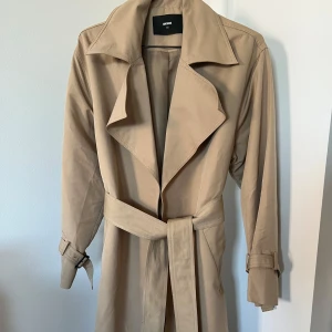 Trenchcoat - Superfin kappa som tyvärr är lite stor på mig. Har ett litet märke men syns knappt då det är bakom kragen. I princip aldrig använd:) Nypris  runt 800kr. 