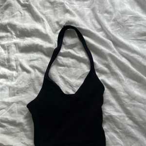 Svart ärmlös topp från H&M Divided - Säljer en stilren svart topp med öppen rygg från H&M. Perfekt för sommardagar eller för festligheter. Toppen är i storlek XXS. (Är använd max 3ggr.)