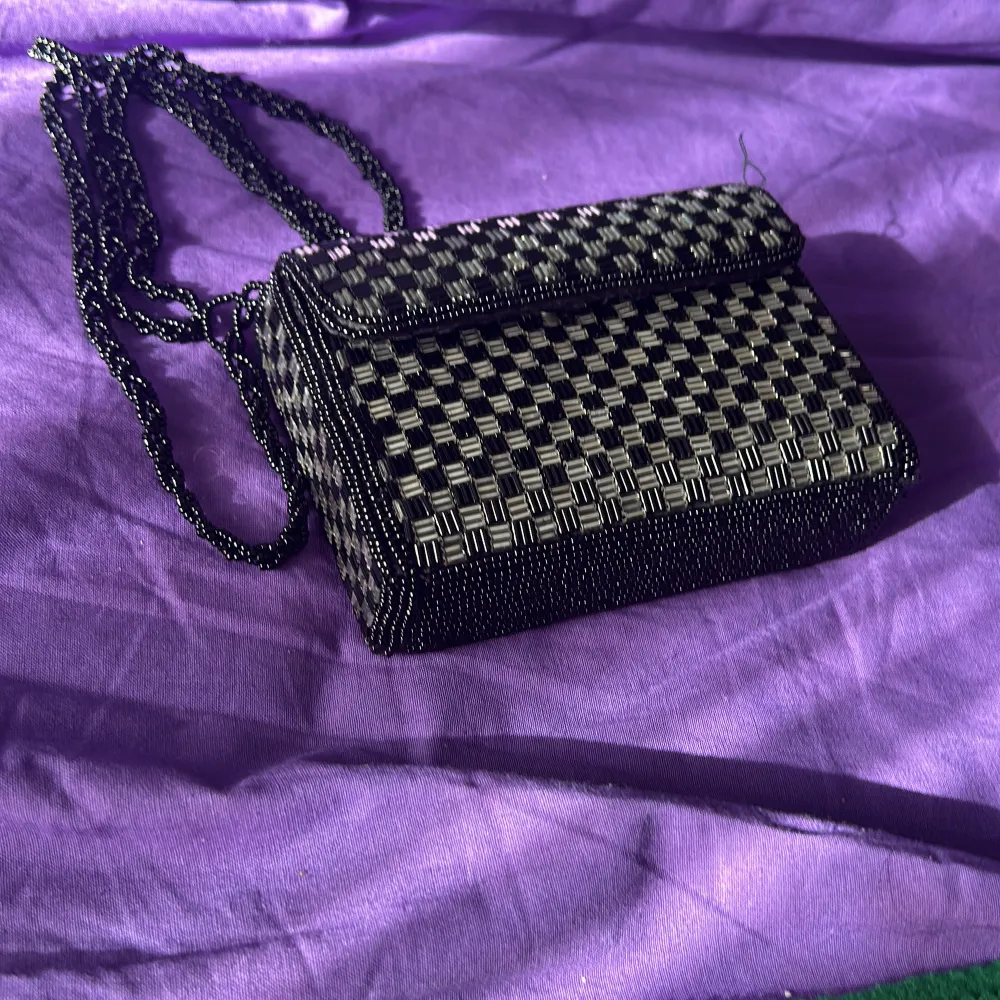 Säljer en supercool axelväska i svart och silver med ett snyggt rutigt mönster. Väskan har en elegant kedja som axelrem och är perfekt för en utekväll eller fest. Den är i nyskick och redo att användas för att ge din outfit det där lilla extra!. Laukut & Käsilaukut.