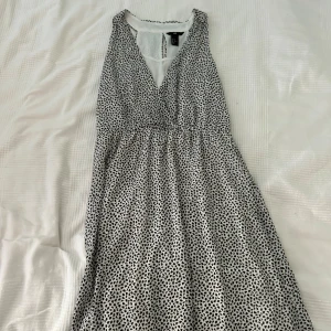 Svartvit prickig klänning från H&M - Säljer en superfin svartvit prickig klänning från H&M. Klänningen har en lös passform och är gjord i ett lätt och bekvämt material. 
