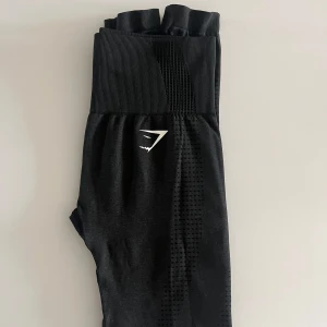 Gymshark träningstights - Träningstights från Gymshark i modellen ”Vital Seamless leggings 2.0”. Aldrig använda, säljes pga en litet hål i sömmen där bak. Fick dessa såhär och kan lagas lätt med lite nål och tråd. Nu fått nya och har därför ingen användning av dessa. 549kr ny