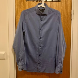 Blå finskjorta, XS - Säljer en av mina finskjortor som jag växt ur. Passformen är slim fit. Axelbredd: 40cm, längd: 71cm. Har bara använt den ett fåtal gånger så den är i fint skick. Se bilder. Frågor? Skicka ett dm!