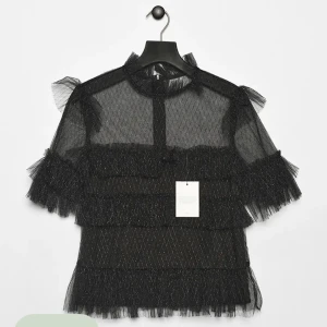 Svart glittrig blus med volanger - Säljer en superfin svart blus med glittriga detaljer från By Malina, modell Rachel. Transparent material, perfekt till fest! Helt oanvänd med lappar kvar. Bilder lånade från Arkivet. Egna bilder går att få. Strl XL men passar strl 38-40.