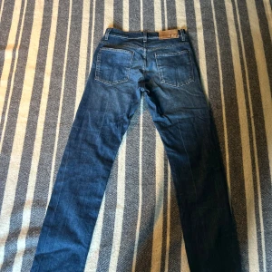 Tiger of Sweden jeans - Snygga blå jeans med klassisk femficksdesign och en bekväm passform. Perfekta för en avslappnad stil. De har en traditionell dragkedja och knappstängning. Skicket är 10/10 och finns inga defekter. W30. Ifall du har fler frågor är det bara att höra av dig!!!