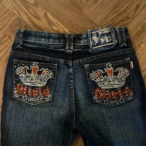 Mörkblå jeans med broderi från YD - Snygga mörkblå jeans från YD med unikt broderi och nitar på fram- och bakfickorna. Inne benlängden är 60cm. Midjemått rakt över är 36 cm. 