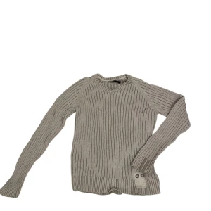 Vit Dentity ribbad tröja - Snygg vit Dentity ribbad tröja med långa ärmar och dekorativa knappar vid nederkanten. Perfekt för en stilren och bekväm look.