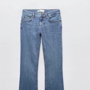 Blå bootcut jeans från Zara - Snygga blå lowwaist bootcut jeans från Zara med klassisk femficksdesign och knappgylf. Perfekta för en avslappnad stil med en touch av retro. Tillverkade i jeansmaterial för en bekväm passform. Lite slitna vid benkanten.