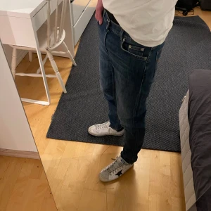 Dondup Jeans - Säljer ett par snygga blå jeans från Dondup med en slim fit. De har en klassisk femficksdesign och en läderpatch med logotyp baktill. Perfekta för en avslappnad stil. Riktigt snygg wash! Nypris 3500kr. Skriv vid funderingar🤝