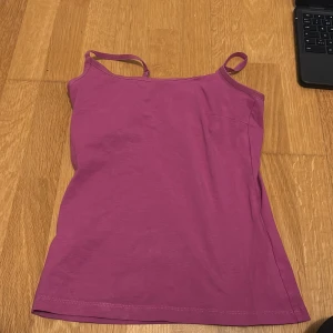 Lila linnetopp - Säljer en enkel och stilren lila linnetopp med smala axelband. Perfekt för varma sommardagar eller som ett lager under en tröja. Toppen är gjord i ett mjukt och bekvämt material.