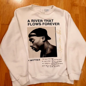 Limited Edition Vit 2PAC hoodie - Säljer en vit sweatshirt från Zara med ett stort tryck av 2PAC och texten 'A RIVER THAT FLOWS FOREVER'. Tröjan har långa ärmar och en rund halsringning. Perfekt för dig som gillar klassiska hiphop-influenser. Finne ej i lager nånstans . Passar till folk som bär S.