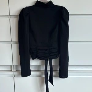 Svart blus med öppen rygg - Säljer min älskade svarta blus med öppen rygg och knytning där bak från Gina Tricot🩷har använts väldigt varsamt  och är därför fortfarande i otroligt bra skick🫶🏻perfekt till en mer festlig kväll!