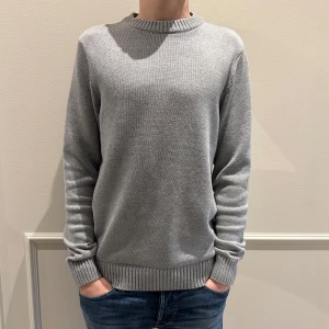 Grå stickad tröja-Dobber - Säljer denna stilrena grå stickade tröja från Dobber. Tröjan är köpt för 899 kr för två månader sedan på MQ men har inte kommit till användning, så den är nästintill som ny. Storlek S, tveka inte på att höra av dig vid minsta fundering kring storlek osv. 