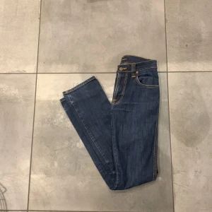Blå jeans från Nudie Jeans Co - Säljer ett par snygga blå jeans från Nudie Jeans Co. Jeansen ger ett otroligt bra intryck. Perfekta för både vardag och fest! Jeansen är inte använda mycket, dom är i så gott som nytt skick! Vid funderingar tveka inte att höra av dig, pris kan diskuteras vid snabb affär!⭐️