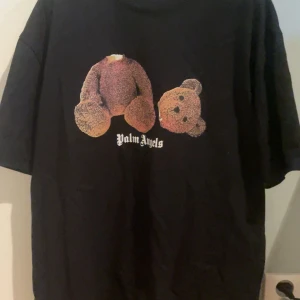 Palm Angels T-shirt - Cool svart t-shirt från Palm Angels med ett unikt nalletryck på framsidan. T-shirten har korta ärmar och en normal passform. Perfekt för en avslappnad stil.