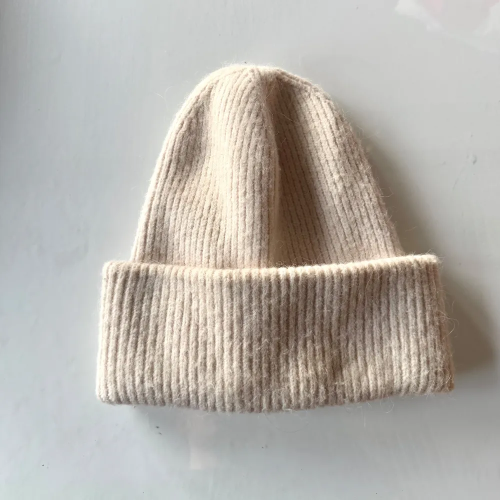 Säljer en stilren beige mössa med ribbad design. Perfekt för kyliga dagar och ger en mysig känsla. Passar till de flesta outfits och är ett måste i garderoben.. Asusteet.
